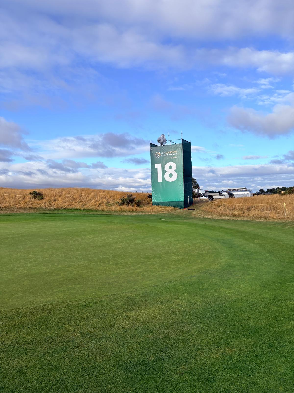 Green-wrapped scaffold camera tower marked 18 on a UK golf green